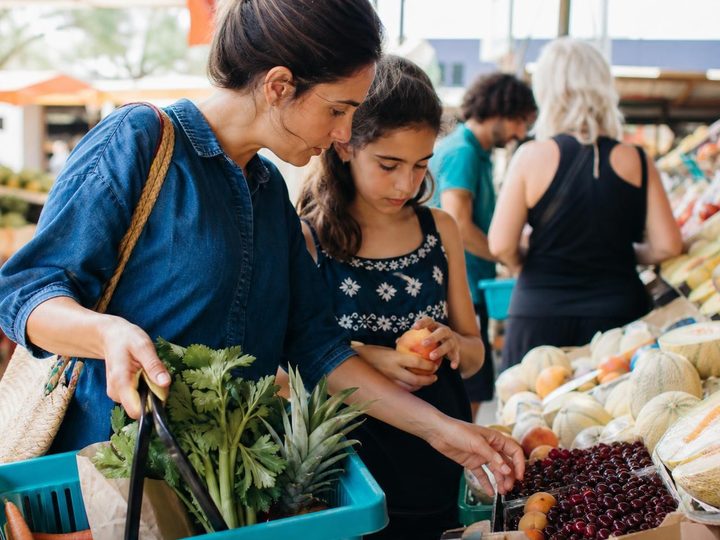 A woman and her daughter buy fruit at a market